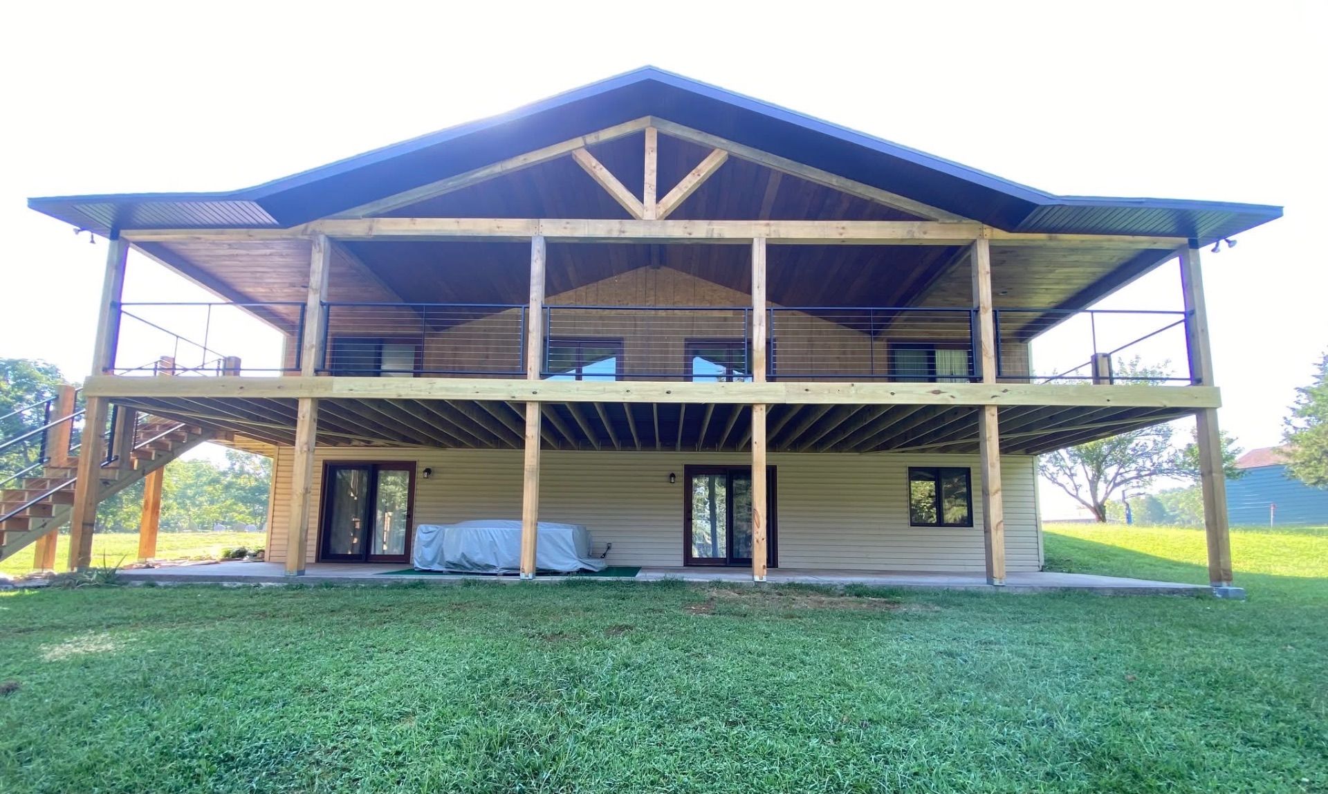 Two-story covered deck with cedar timber frame and black horizontal metal railing