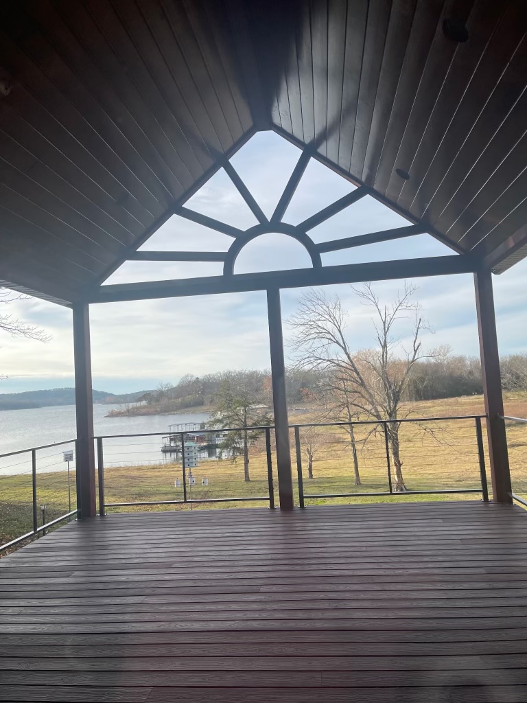 Covered deck with custom sunburst gable window overlooking the lake