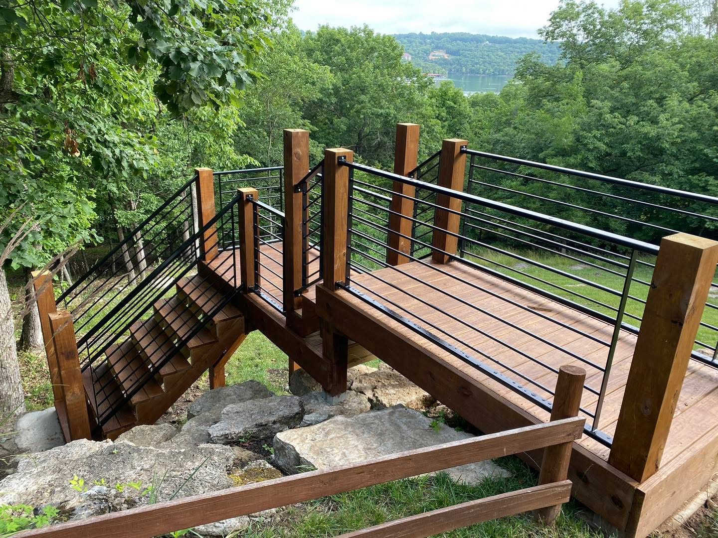 Wood deck landing with welded black horizontal metal railing and matching stair rail